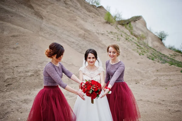 포즈를 취하는 그녀의 결혼식에 모래 채 석에서 그녀의 신부 들러리와 신부 — 스톡 사진