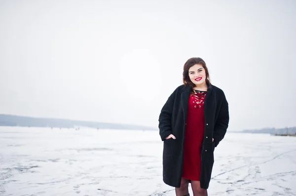 Morena modelo de talla grande en rojo contra el lago congelado en invierno da —  Fotos de Stock