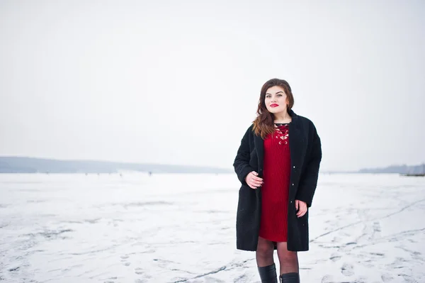 Morena plus size modelo em vermelho contra lago congelado no inverno da — Fotografia de Stock