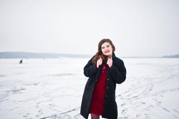 Morena modelo de talla grande en rojo contra el lago congelado en invierno da —  Fotos de Stock