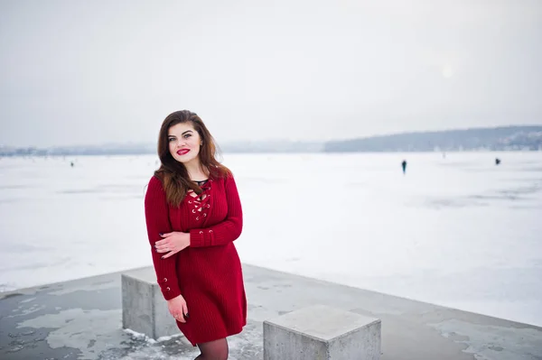 Morena modelo de talla grande en rojo contra el lago congelado en invierno da —  Fotos de Stock