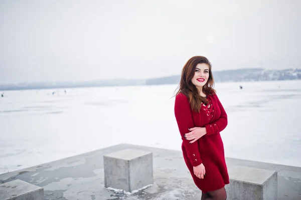 Morena modelo de talla grande en rojo contra el lago congelado en invierno da —  Fotos de Stock