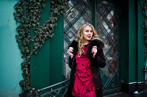 Elegancia chica rubia en vestido de noche rojo y abrigo de piel en la calle — Foto de Stock