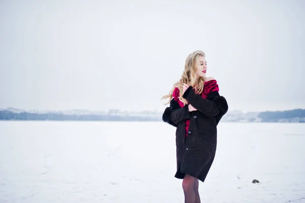 Eleganci blondýna v kožichu a červené večerní šaty představují na — Stock fotografie