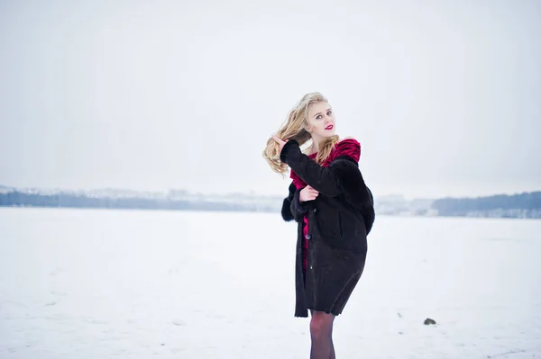 Elegancia chica rubia en abrigo de piel y vestido de noche rojo posado en — Foto de Stock