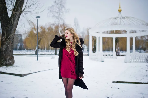 Elegance blonde girl in fur coat and red evening dress posed at — Stock Photo, Image