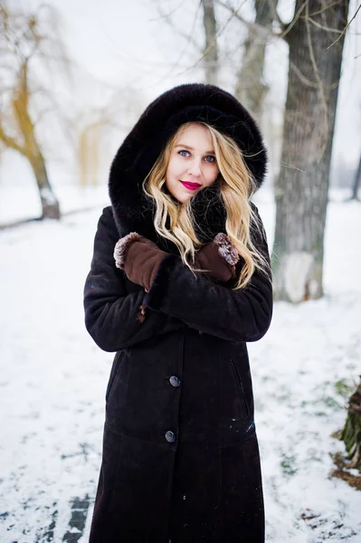 Élégante fille blonde en manteau de fourrure et robe de soirée rouge posée à — Photo