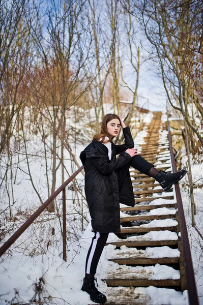 Módní dlouhé nohy brunetka model v dlouhém černém plášti, které představují o — Stock fotografie