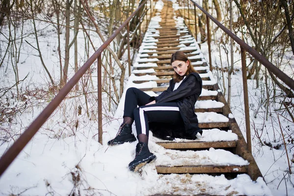 Módní dlouhé nohy brunetka model v dlouhém černém plášti, které představují o — Stock fotografie