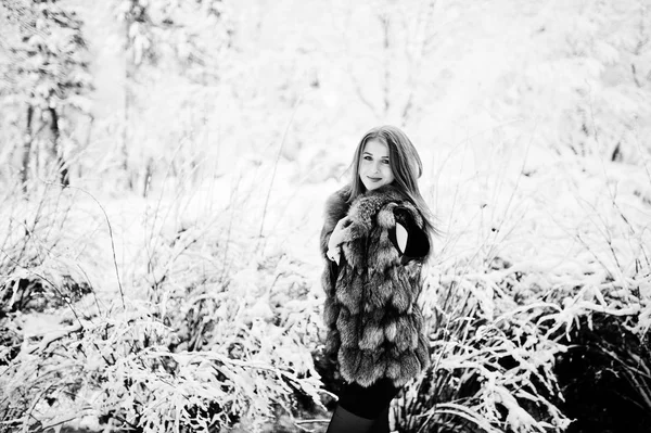 Червона волохата дівчина в шубці йде в зимовому засніженому парку . — стокове фото