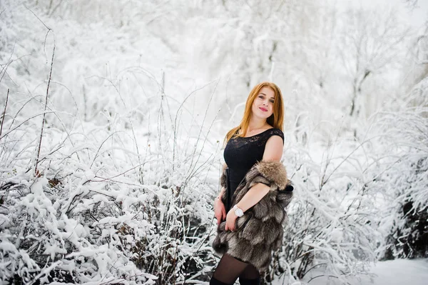 Chica pelirroja en abrigo de piel caminando en el parque nevado de invierno . —  Fotos de Stock