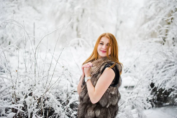 Chica pelirroja en abrigo de piel caminando en el parque nevado de invierno . —  Fotos de Stock