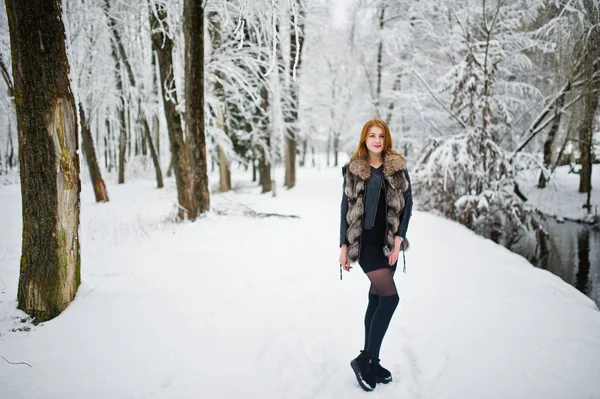 Rood harige meisje in bontjas wandelen in winter besneeuwde park. — Stockfoto