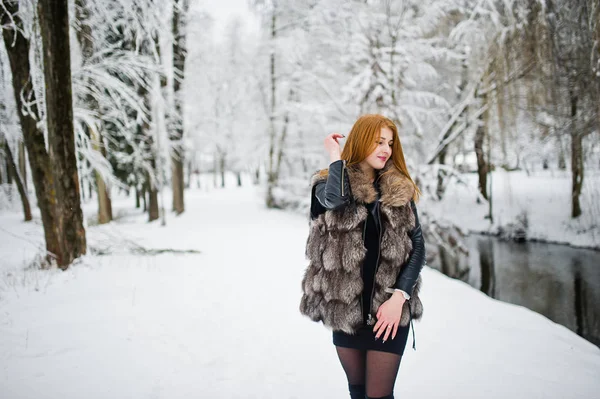겨울 눈 덮인 공원에서 산책 하는 모피 코트에서 붉은 머리의 소녀. — 스톡 사진