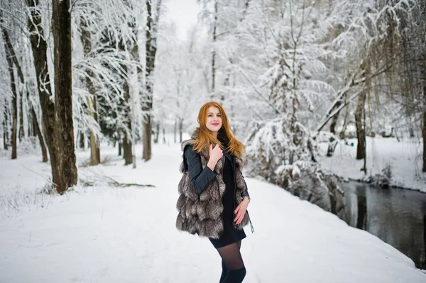 Chica pelirroja en abrigo de piel caminando en el parque nevado de invierno . —  Fotos de Stock