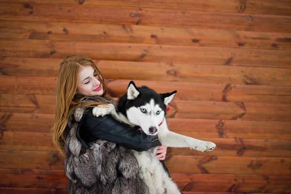 Rudowłosy dziewczyna z psem husky drewnianą ścianę. — Zdjęcie stockowe