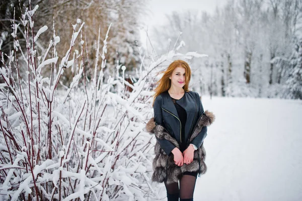 Rood harige meisje in bontjas wandelen in winter besneeuwde park. — Stockfoto