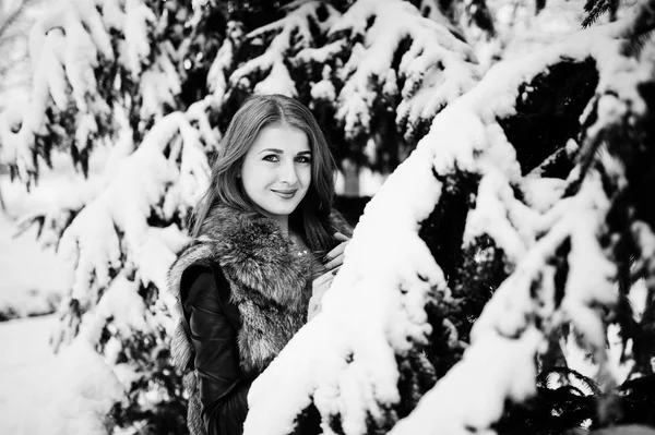 Menina de cabelos vermelhos em casaco de pele andando no parque nevado de inverno . — Fotografia de Stock