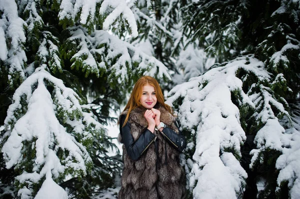 红头发的女孩穿着毛皮大衣在冬天下雪的公园散步. — 图库照片