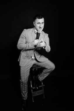 Siyah backgrou karşı mikrofon ile gri elbiseli yakışıklı adam