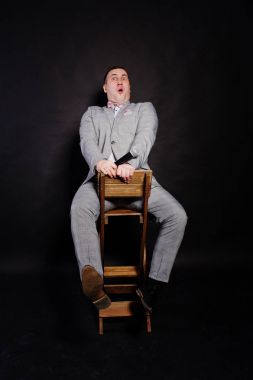 Siyah backgrou karşı mikrofon ile gri elbiseli yakışıklı adam