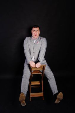 Siyah backgrou karşı mikrofon ile gri elbiseli yakışıklı adam