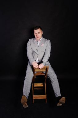 Siyah backgrou karşı mikrofon ile gri elbiseli yakışıklı adam