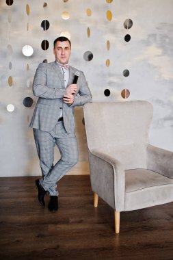 Sandalye backgrou karşı mikrofon ile gri elbiseli yakışıklı adam