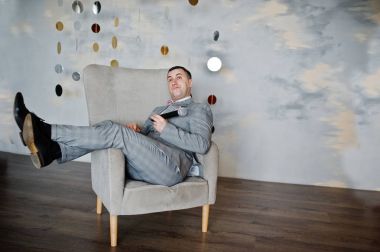 Sandalye backg üzerinde oturan mikrofon ile gri elbiseli yakışıklı adam