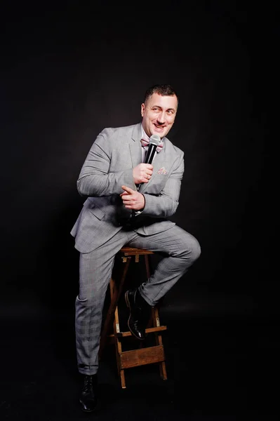 Όμορφος άνδρας στο γκρι κοστούμι με μικρόφωνο ενάντια μαύρο λεμονάτα — Φωτογραφία Αρχείου