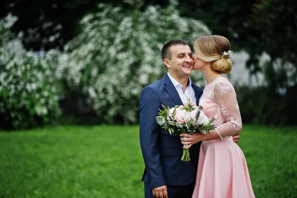 Pareja joven enamorada contra los arbustos de primavera. Chica con ramo . — Foto de Stock