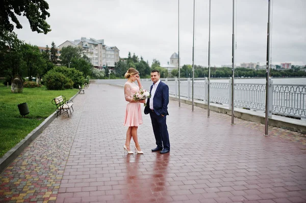 Young couple in love walking the waterfront. Girl with bouquet. — Stock Photo, Image