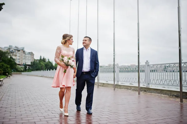 Young couple in love walking the waterfront. Girl with bouquet. — Stock Photo, Image