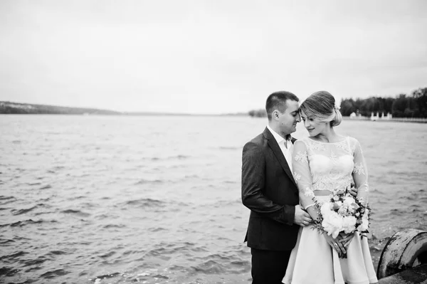 Giovane coppia innamorata contro lago. Ragazza con bouquet . — Foto Stock