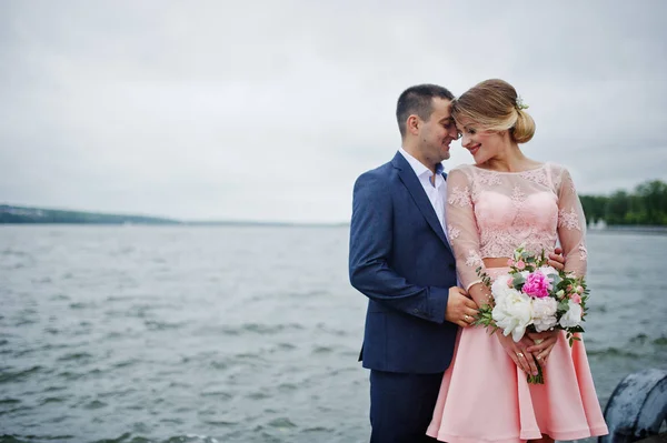 Giovane coppia innamorata contro lago. Ragazza con bouquet . — Foto Stock