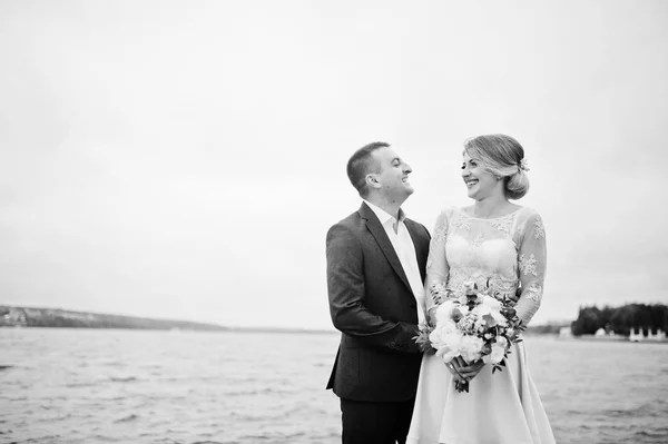 Giovane coppia innamorata contro lago. Ragazza con bouquet . — Foto Stock