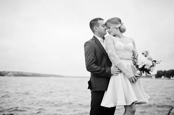 Junges verliebtes Paar gegen See. Mädchen mit Blumenstrauß. — Stockfoto