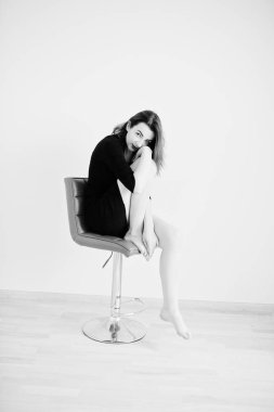 Kırmızı saçlı kız kırmızı sandalye agains üzerinde oturan siyah elbise tunik