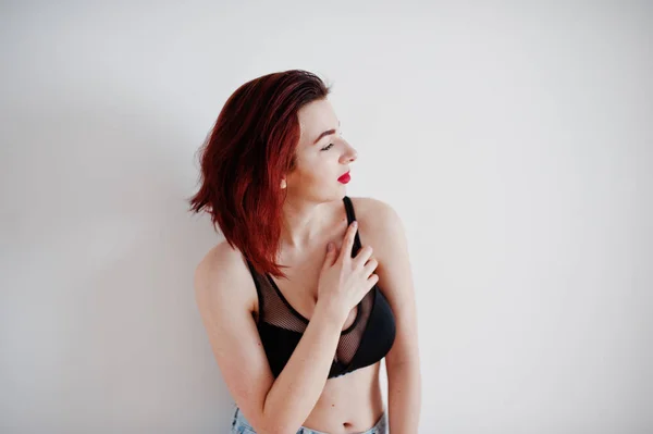 Red haired girl with a big bust on black bra and jeans against w — Stock Photo, Image