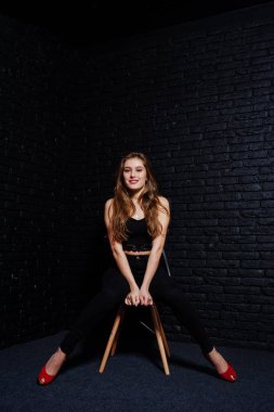 Yakışıklı esmer kız giymek oturan siyah ve kırmızı yüksek topuklar üzerinde