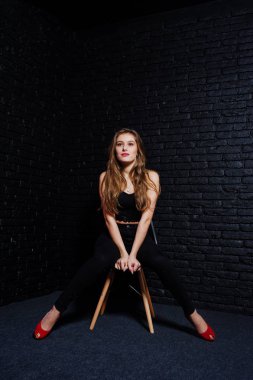 Yakışıklı esmer kız giymek oturan siyah ve kırmızı yüksek topuklar üzerinde