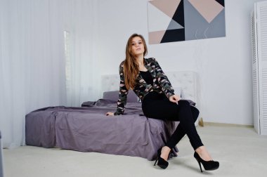 Yakışıklı esmer kız yatakta stu, poz asker gömleği giymek