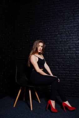 Yakışıklı esmer kız giymek oturan siyah ve kırmızı yüksek topuklar üzerinde