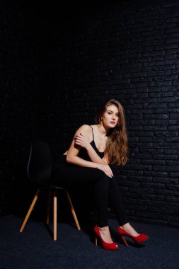 Yakışıklı esmer kız giymek oturan siyah ve kırmızı yüksek topuklar üzerinde