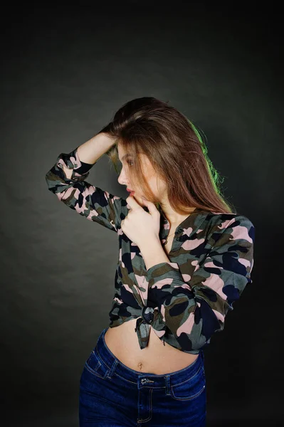 Knappe brunette meisje dragen militaire shirt en spijkerbroek, poseren op — Stockfoto