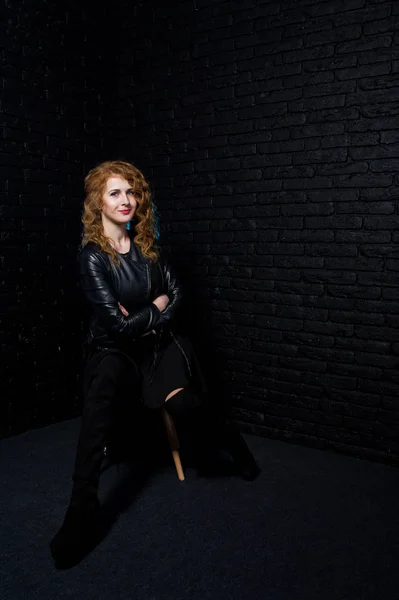 Curly hair girl at leather jacket on studio against black brick — Stock Photo, Image