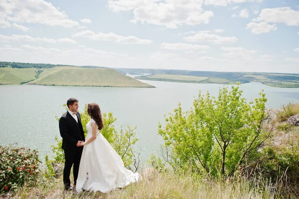 Hochzeitspaar in atemberaubender Landschaft mit Fels und See. — Stockfoto