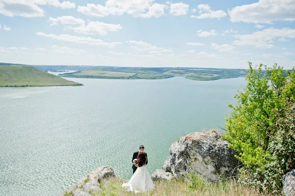 Pareja de bodas en un paisaje impresionante con roca y lago . — Foto de Stock