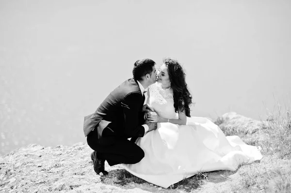 Hochzeitspaar in atemberaubender Landschaft mit Fels und See. — Stockfoto