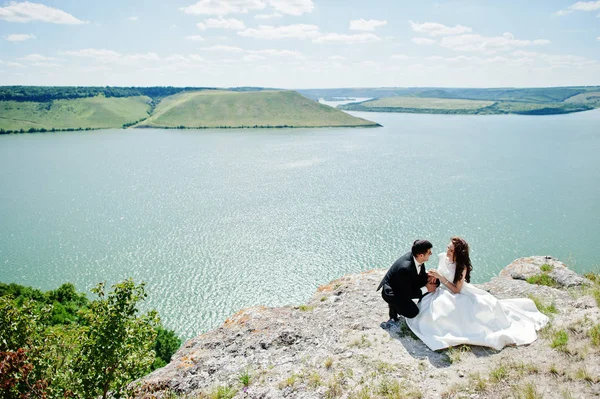 Pareja de bodas en un paisaje impresionante con roca y lago . — Foto de Stock